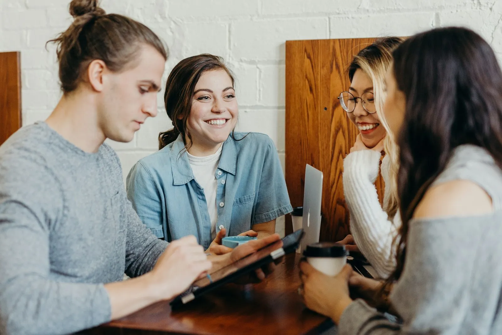 Groupe de jeunes adultes échangeant et riant ensemble autour d'une table en bois